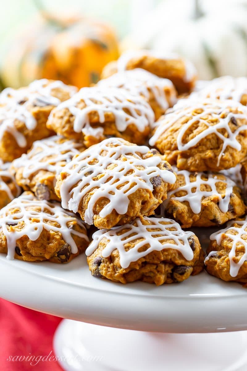 A cake tray piled with pumpkin chocolate chip cookies drizzled with icing