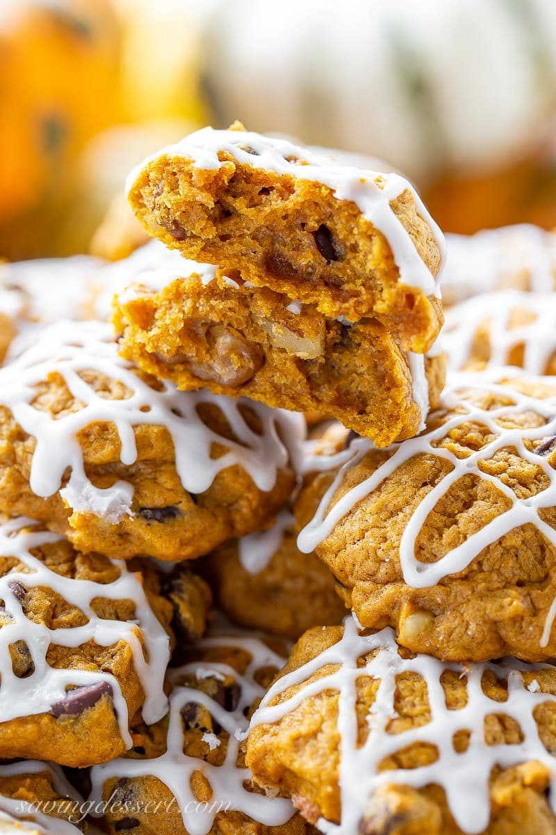 A stack of pumpkin chocolate chip cookies with walnuts drizzled with icing