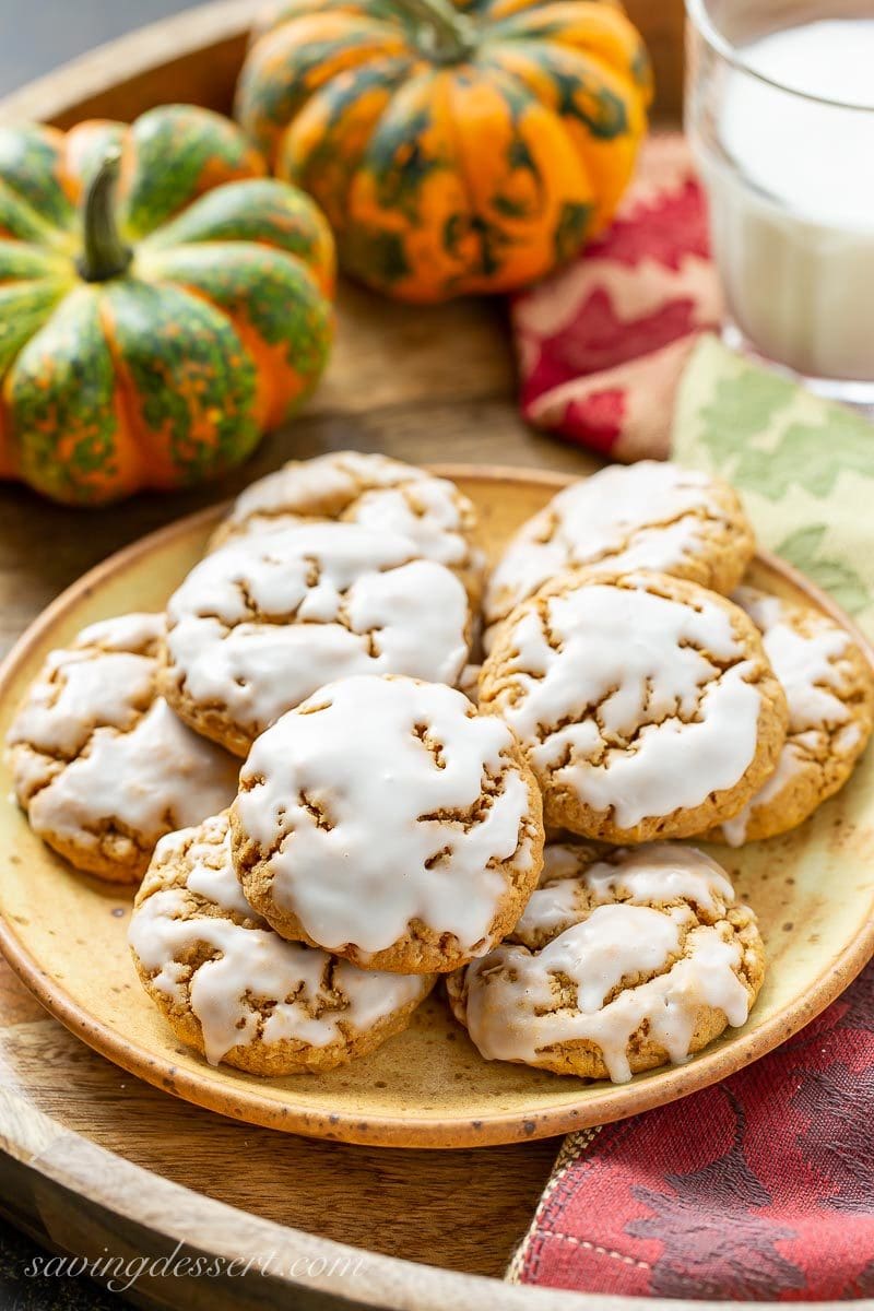 A plate of Spiced Pumpkin Oatmeal Cookies with pumpkins and a glass of milk