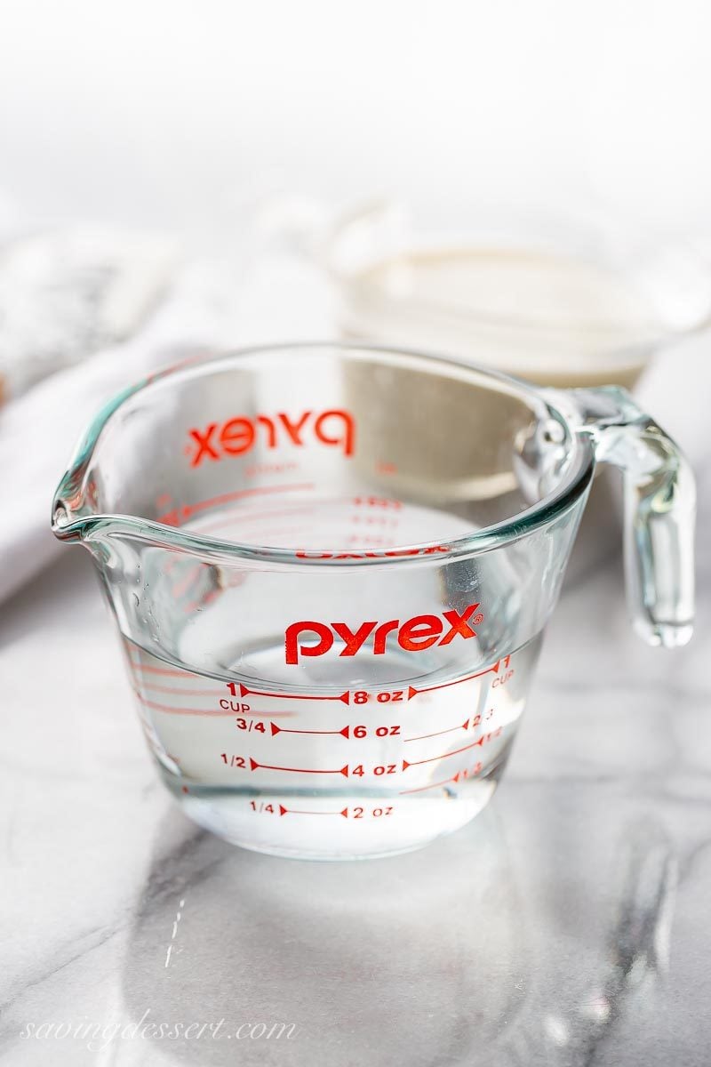A glass measuring cup with a spout, filled with water