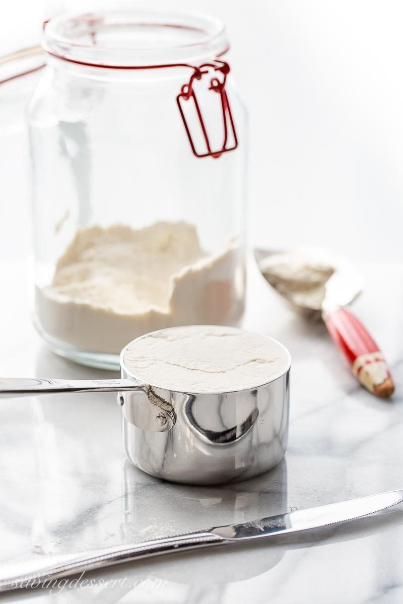 A jar of flour and a measuring cup