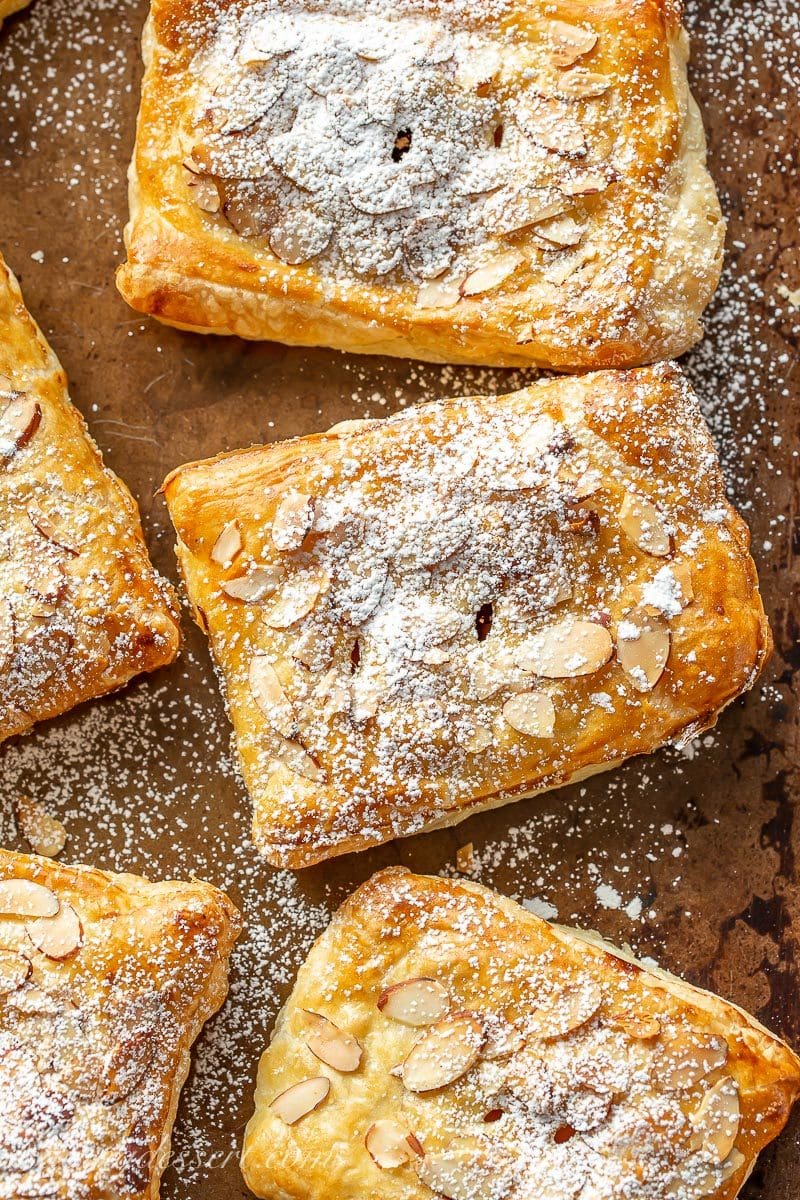 Apple cranberry puff pastry tarts dusted with powdered sugar on a baking pan