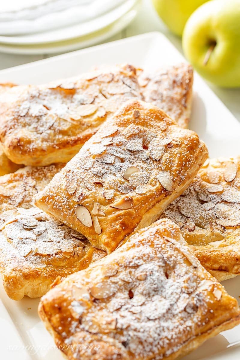 A platter of fresh made apple puff pastry tarts topped with sliced almonds and sprinkled with powdered sugar