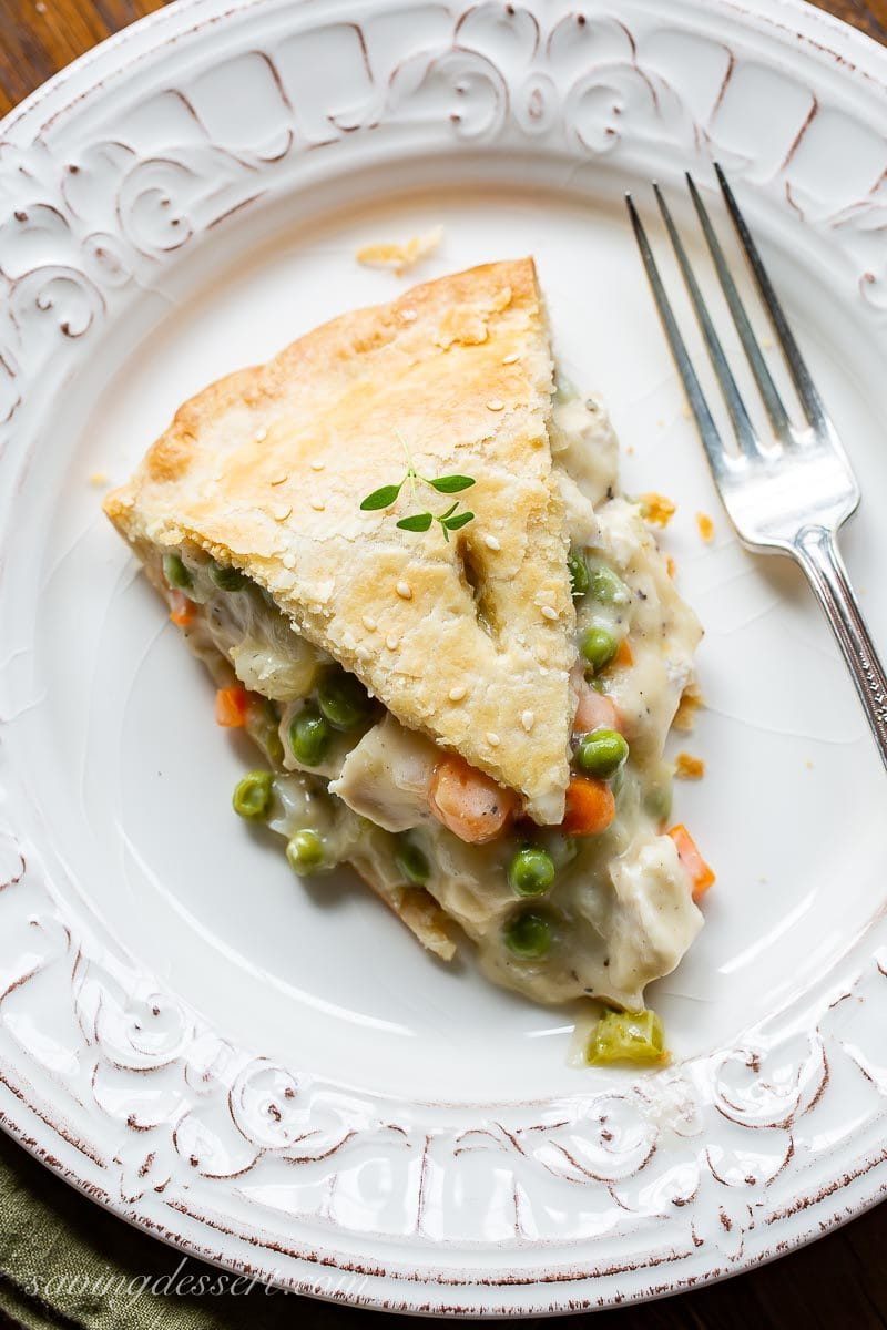 A slice of double crust turkey pot pie with peas, carrots and fresh thyme