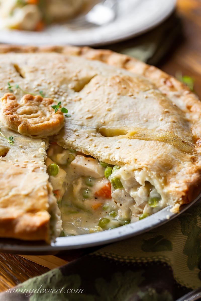 A sliced savory turkey pot pie with chunks of turkey, peas and carrots and a flaky crust