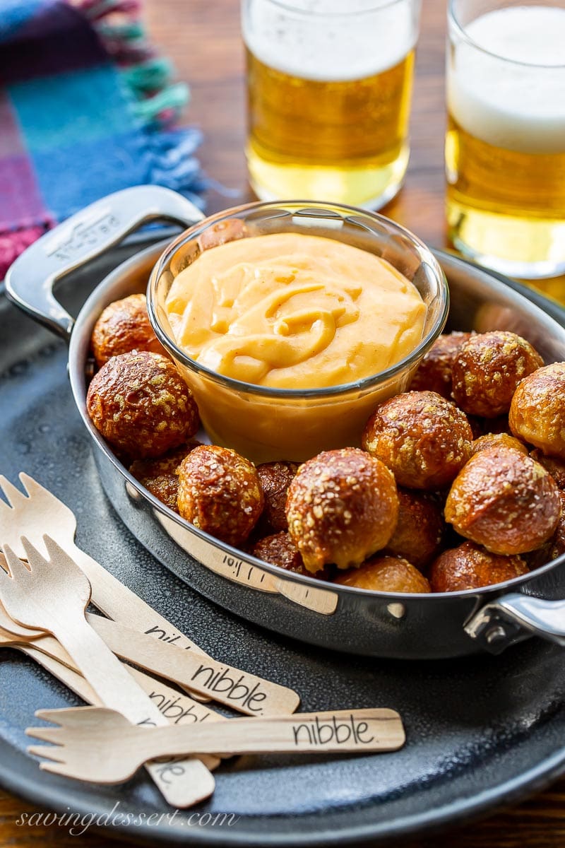 A casserole dish with soft pretzel nuggets and hot, creamy beer cheese dip