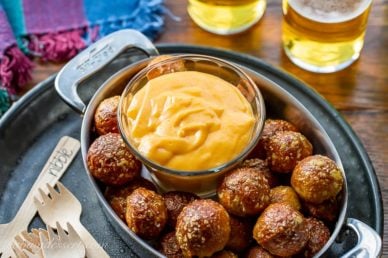 A small bowl of beer cheese dip served with pretzel nuggets