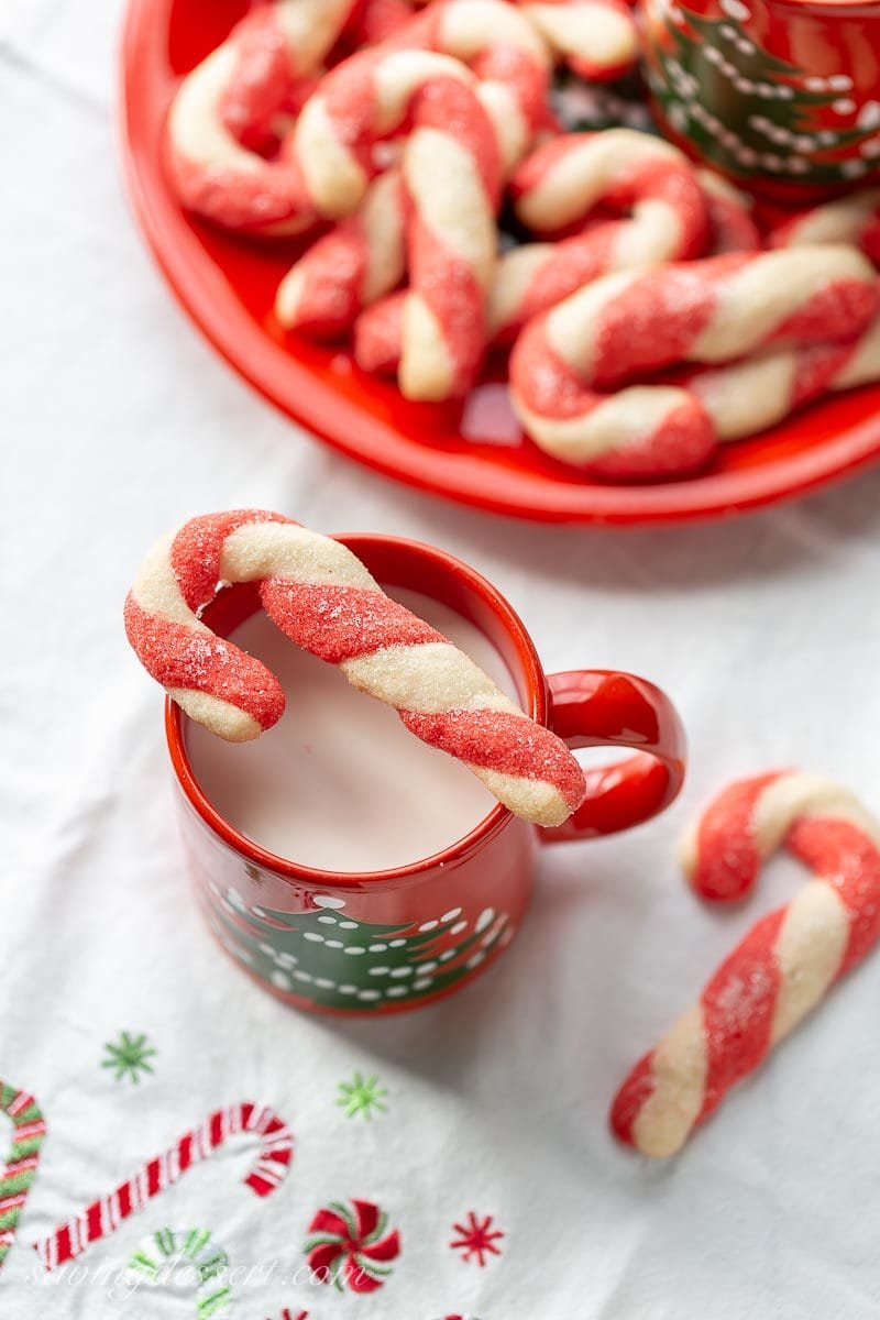 A mug of milk and a peppermint flavored candy cane cookie