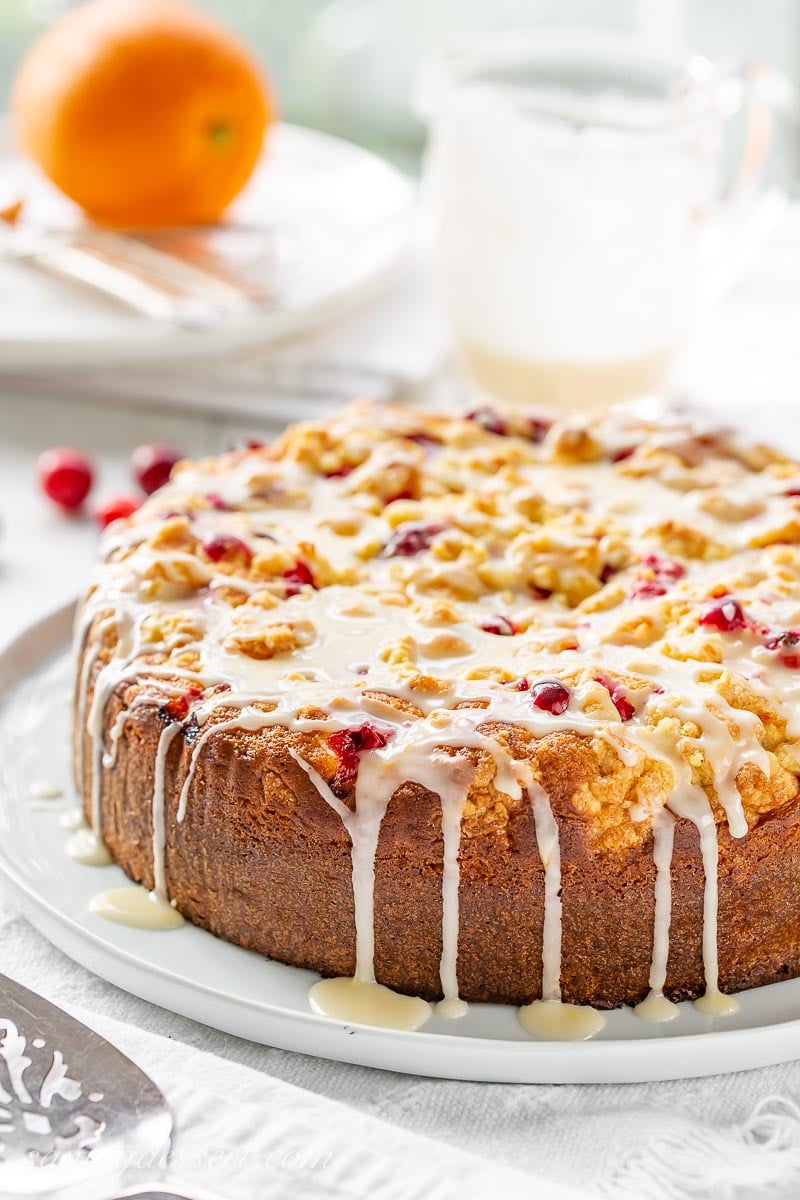 A side view of a tall cranberry cake drizzled with orange icing