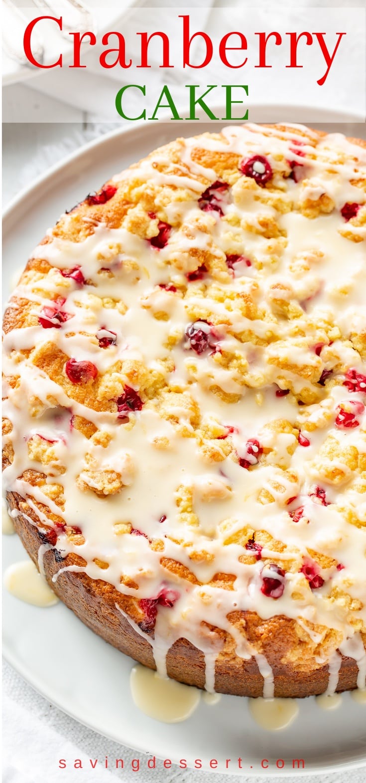 An overhead view of a cranberry cake with a crumble top drizzled with an orange glaze