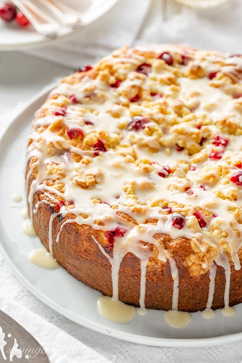 A cranberry cake with orange zest and a crumble top drizzled with an orange glaze