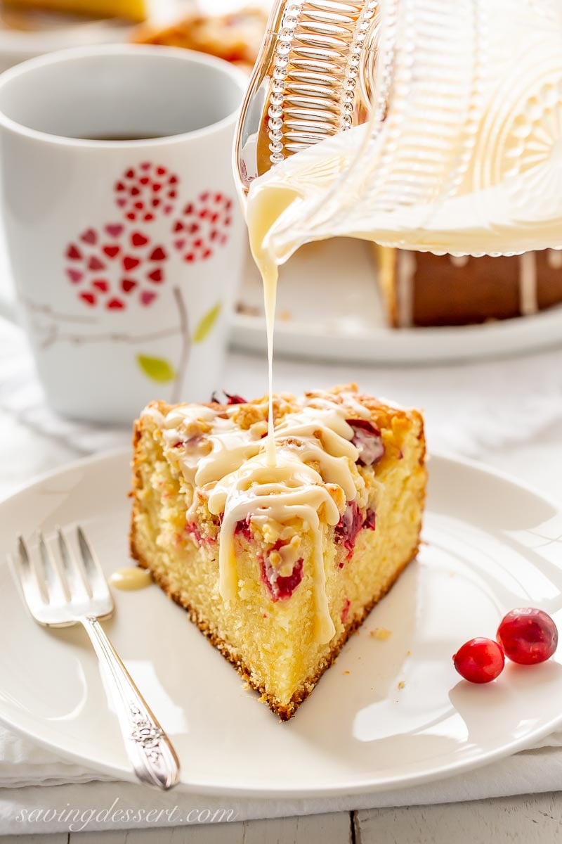 A slice of cranberry cake being drizzled with orange icing