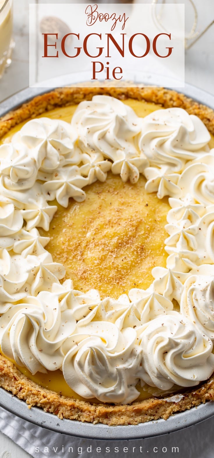 An overhead view of a creamy eggnog pie decorated with whipped cream swirls and a dusting of nutmeg