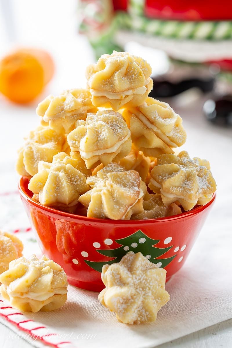 A bowl of orange cream star shaped cookies sandwiched with orange icing