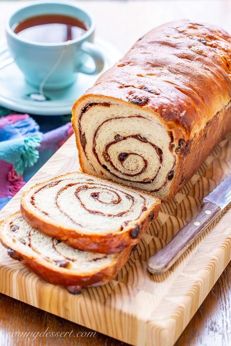A sliced loaf of cinnamon raisin bread with a cup of tea