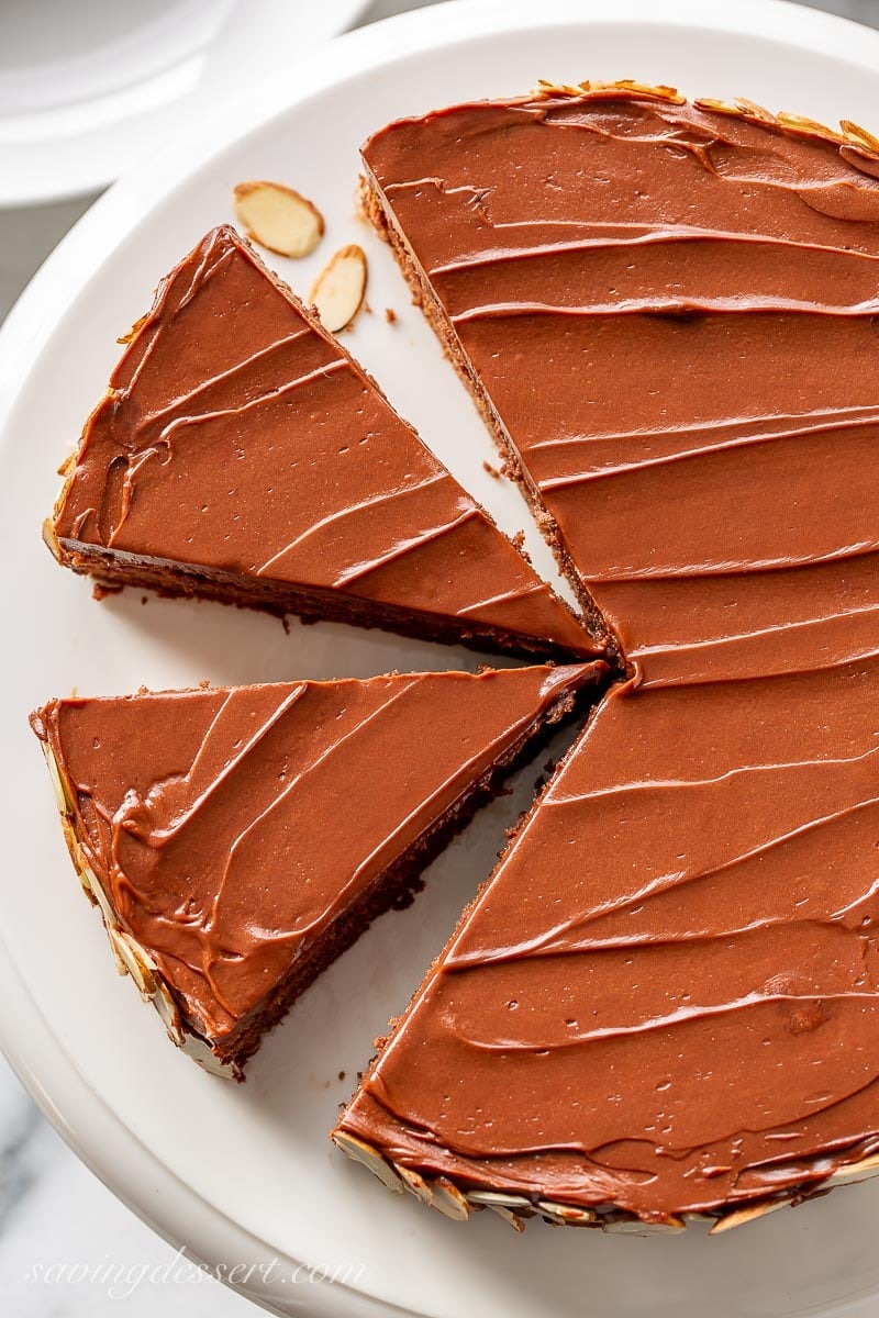 A sliced chocolate almond cake topped with chocolate icing