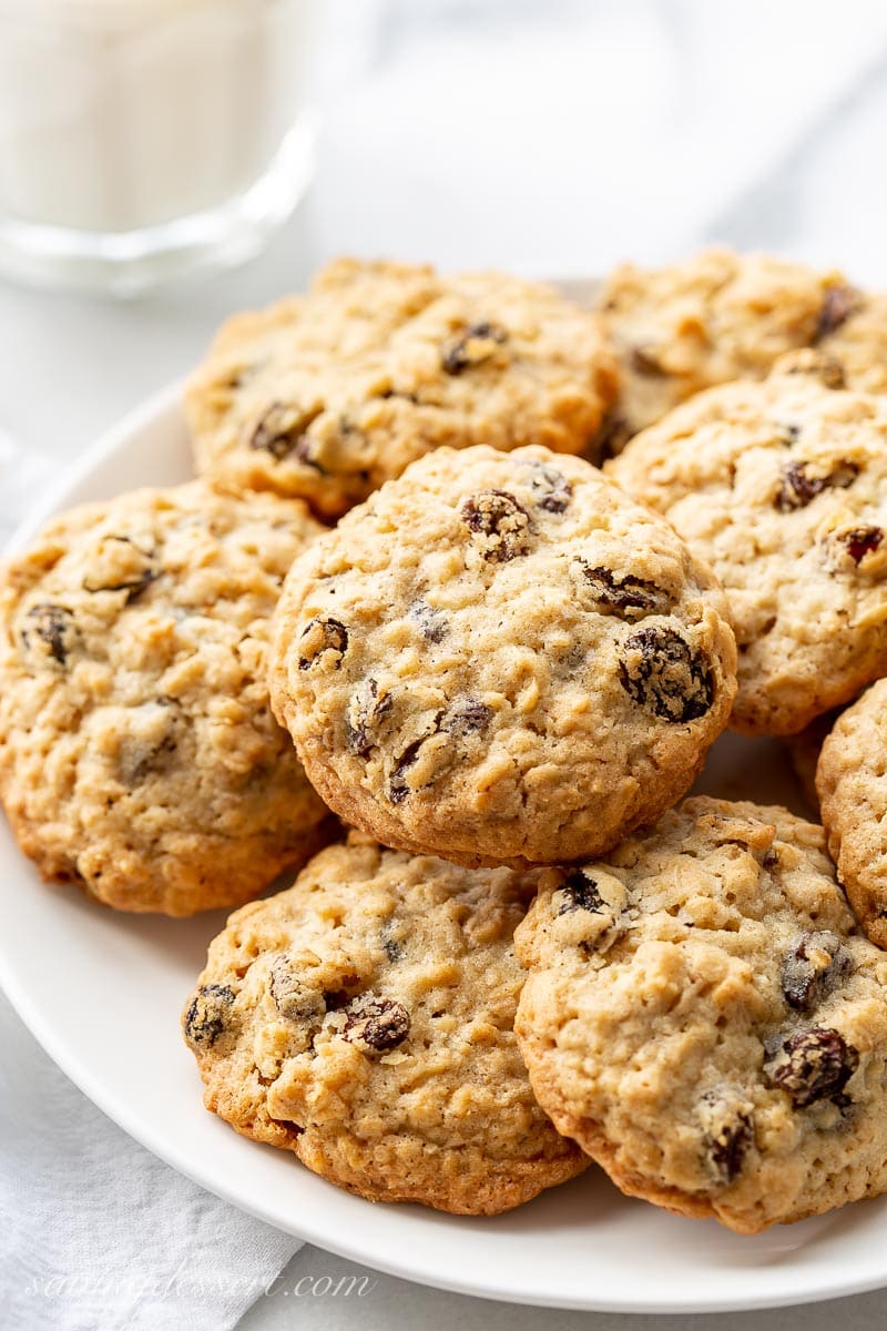 A plate of oatmeal raisin cookies with a glass of milk