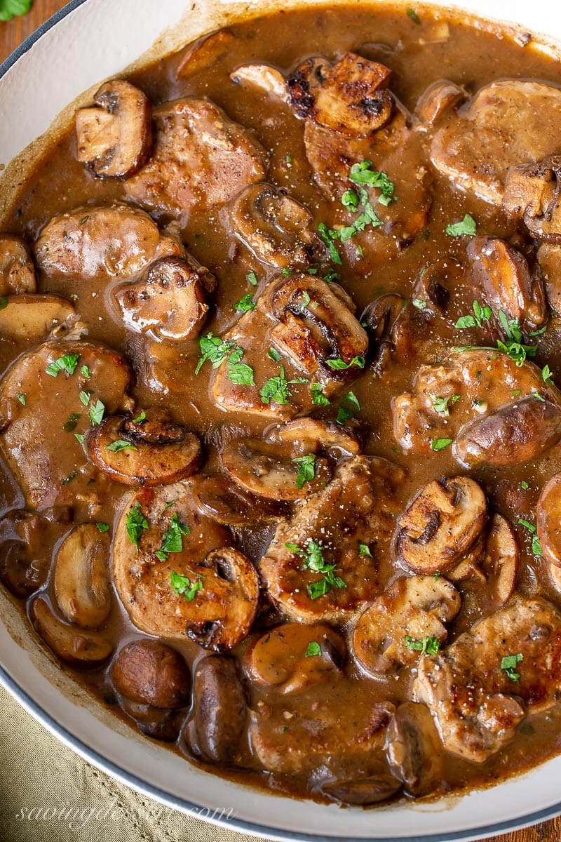 A skillet filled with pork medallions nestled in a mushroom gravy