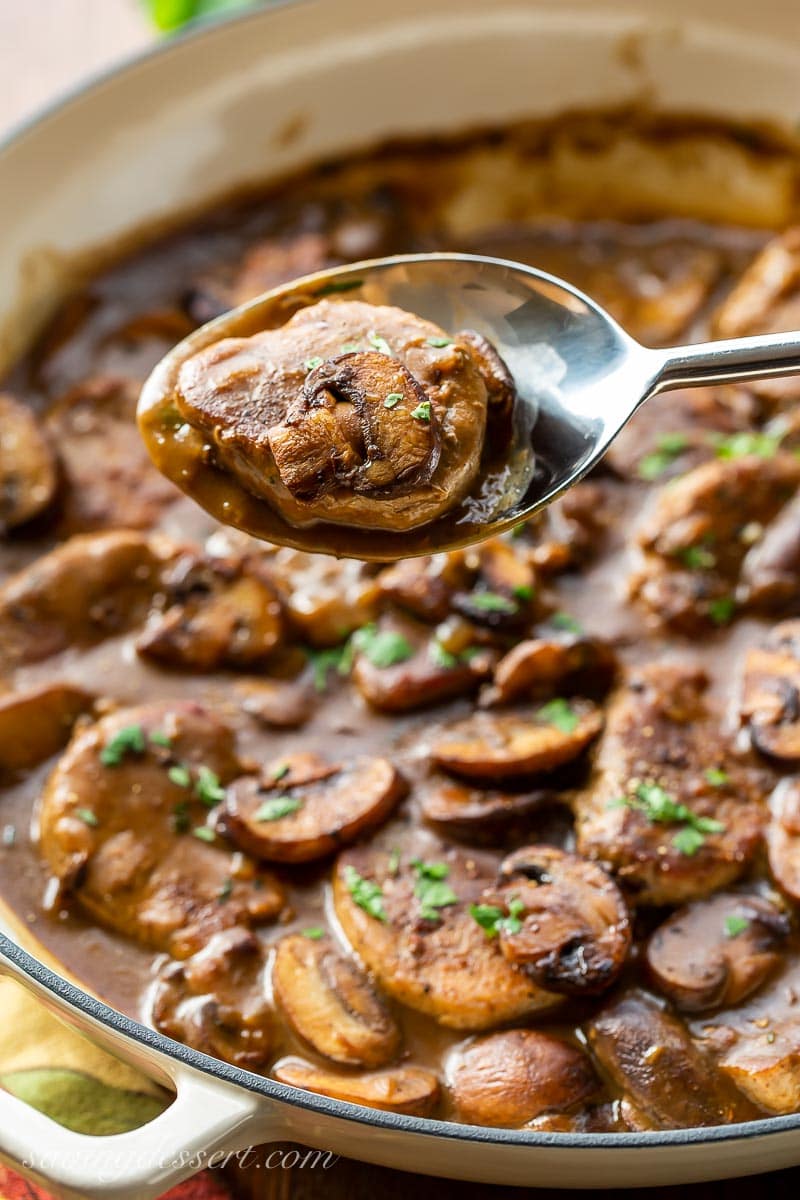 A spoonful of pork and mushrooms in gravy over a skillet