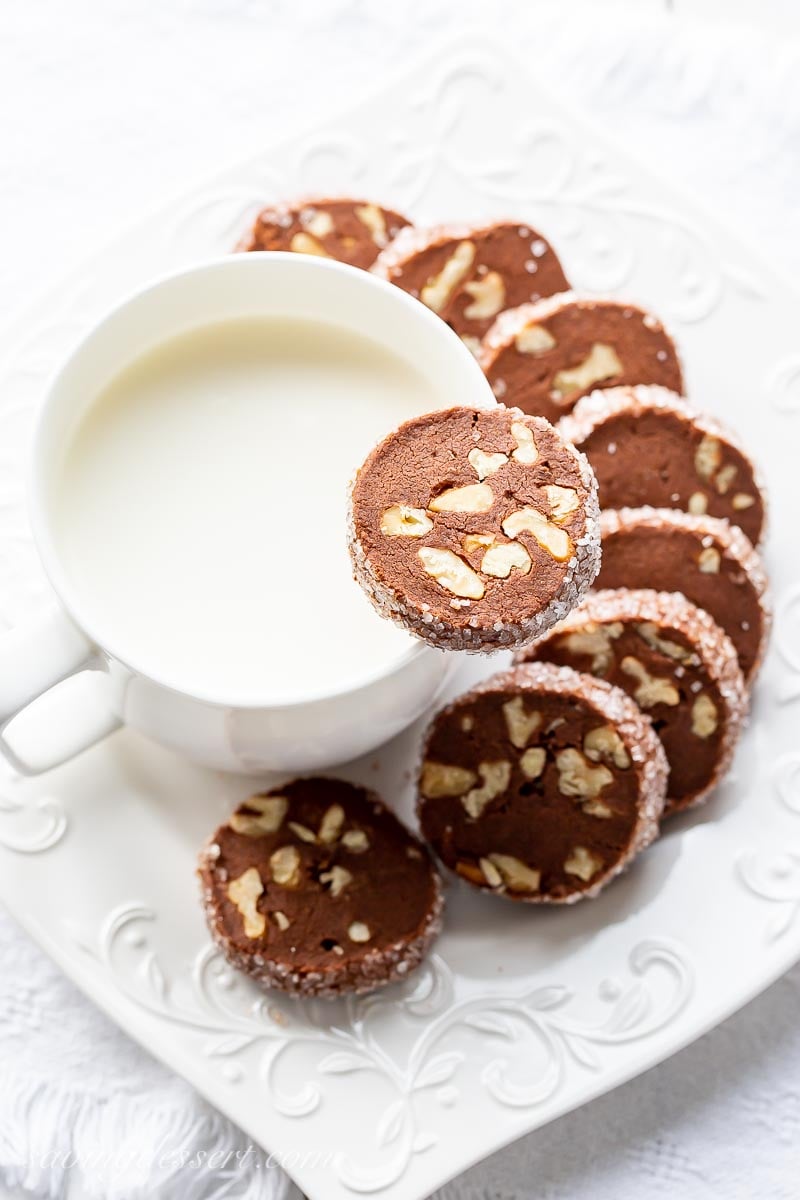 A plate of chocolate walnut cookies with a cup of milk