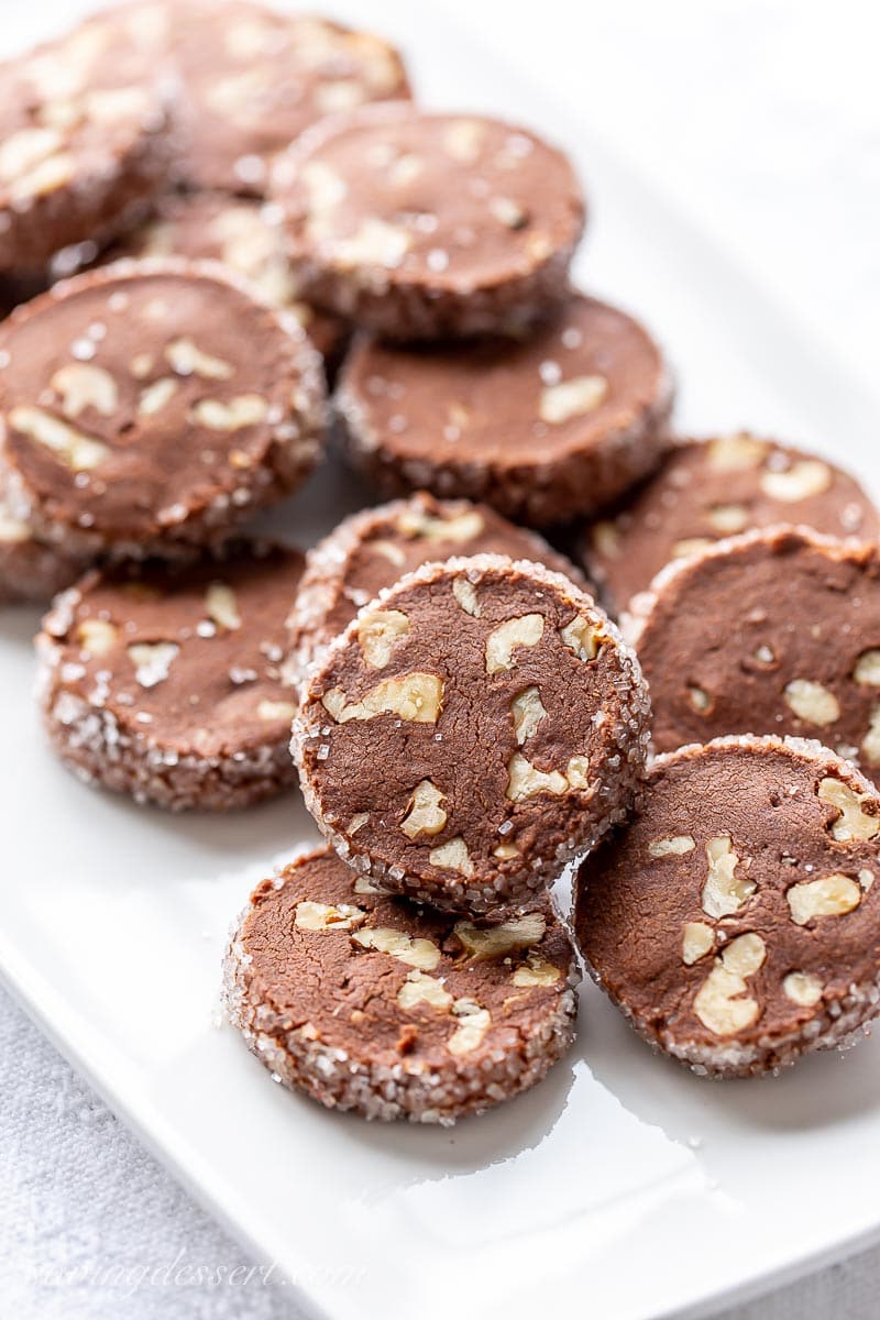 A platter of chocolate shortbread cookies with walnuts and a coarse decorative sugar coating