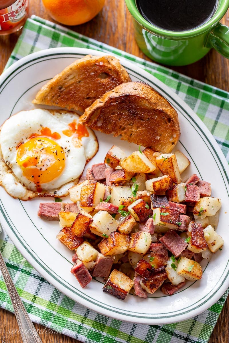 A plate of corned beef hash served with a fried egg, toast and coffee