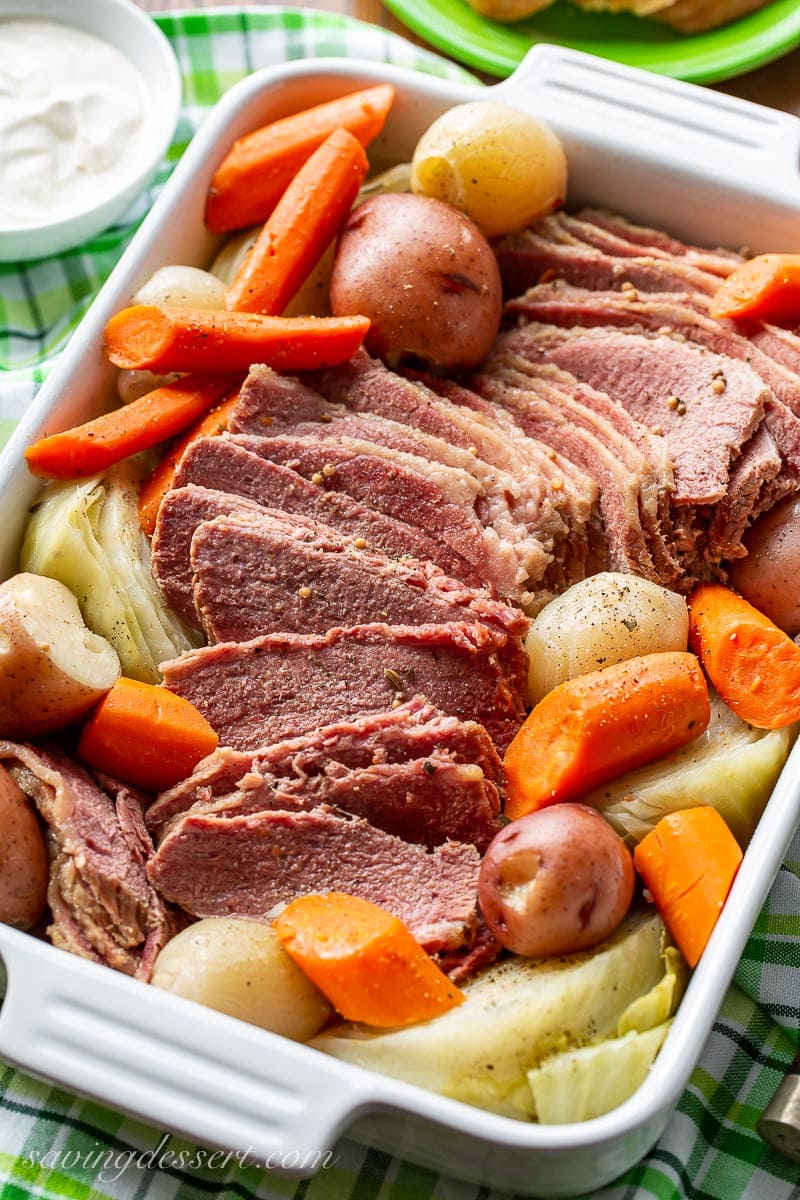 Corned beef and cabbage served with potatoes, carrots and onions and a side of mustard sauce