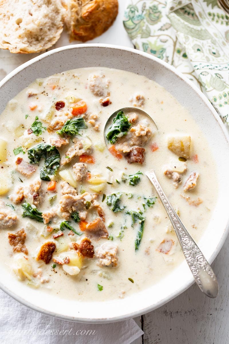 A bowl of Zuppa Toscana Soup with kale, bacon, sausage and potatoes served with a hunk of bread