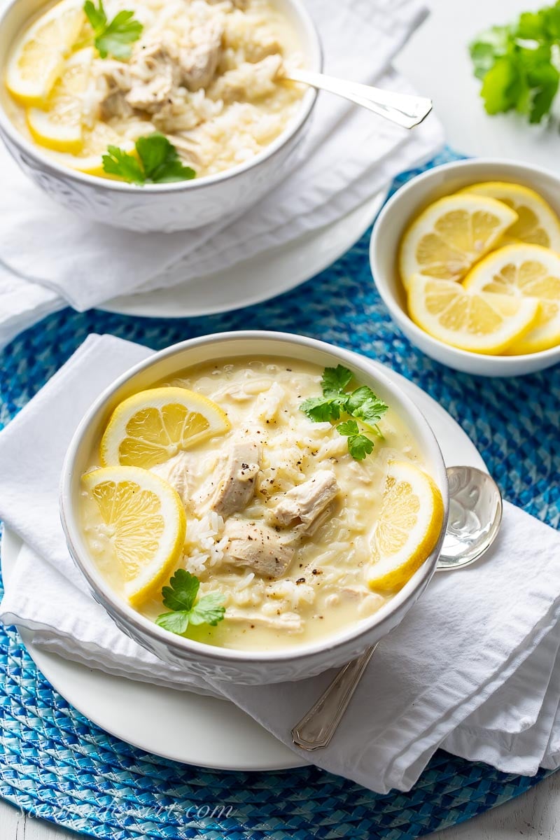 Bowl of Greek chicken and rice soup garnished with lemons and parsley