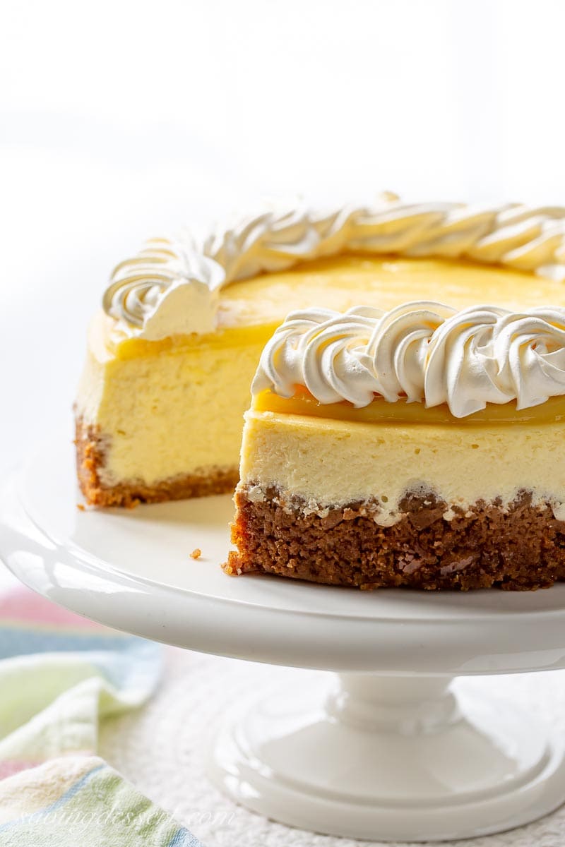 A sliced cheesecake on a cake stand with a lemon curd topping