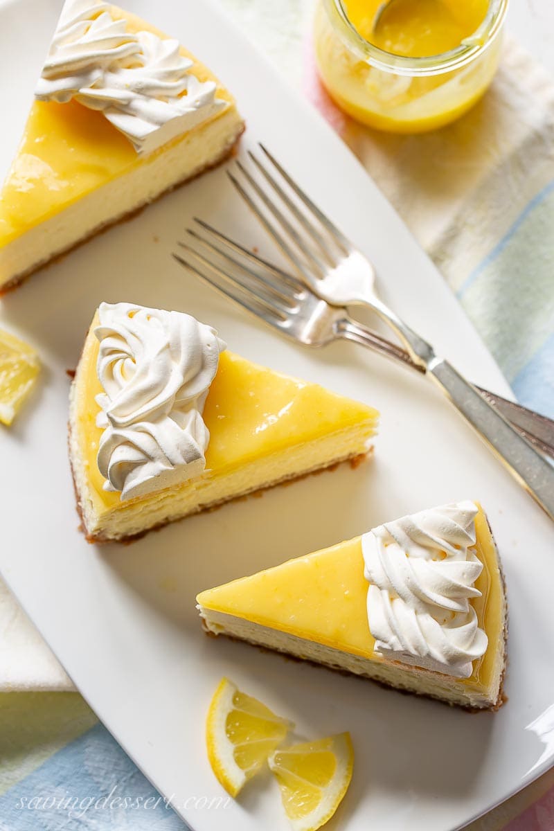 Slices of lemon cheesecake on a platter with a whipped cream topping