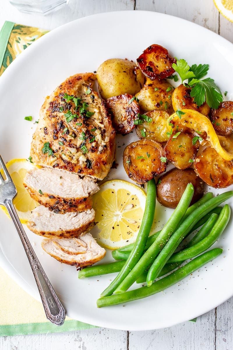 A plate of chicken, potatoes, green beans and lemon