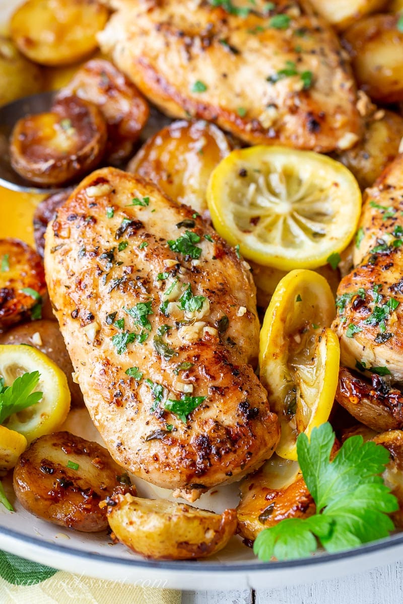 A close up of chicken breasts garnished with parsley and lemon slices