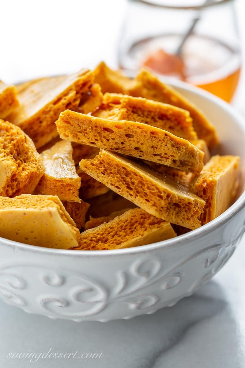 A closeup of honeycomb candy in a bowl, with an airy texture and deep golden color