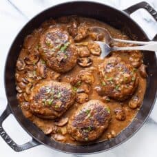 A skillet with salisbury steak and mushroom gravy