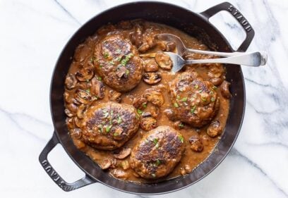 A skillet with salisbury steak and mushroom gravy