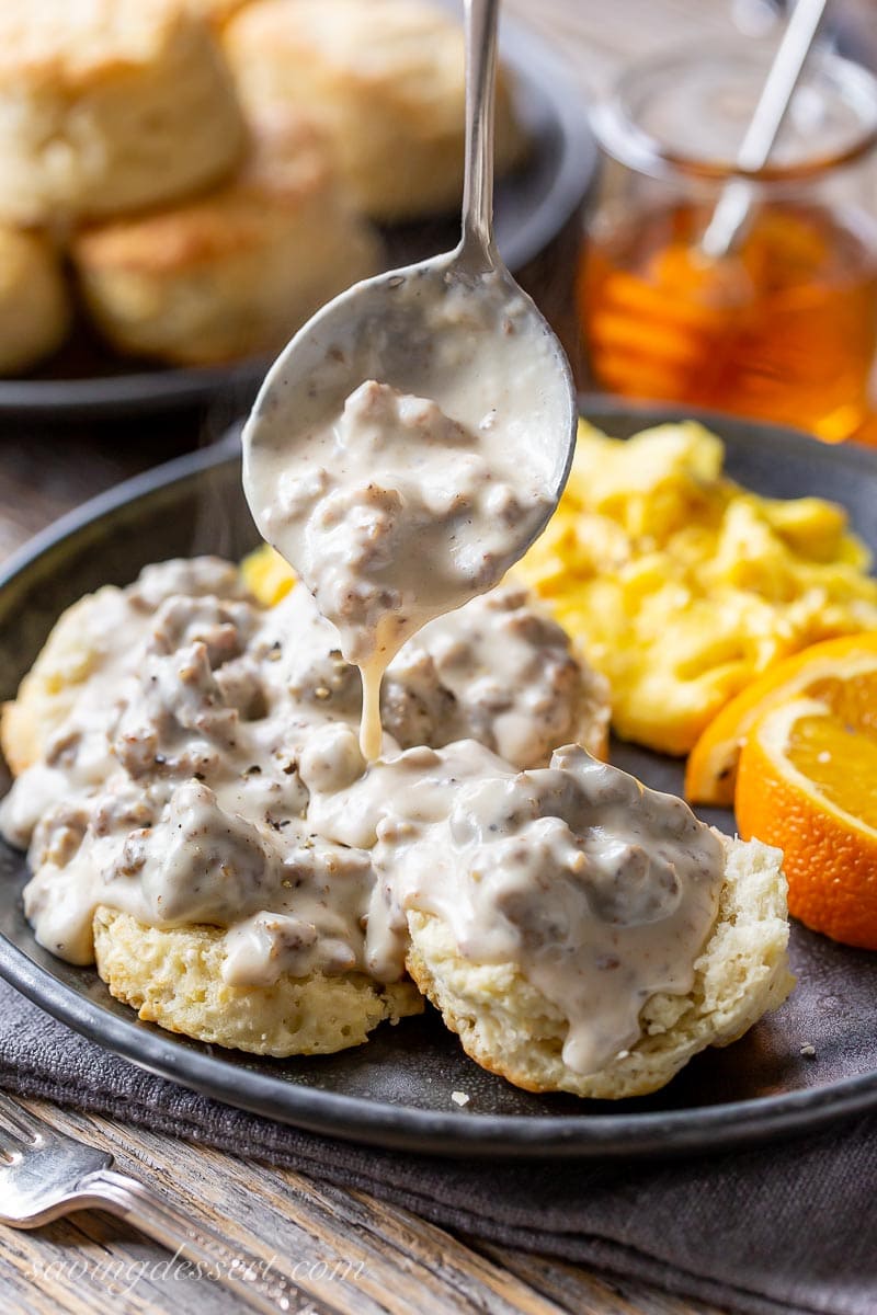 A plate of fresh biscuits being smothered in homemade sausage gravy