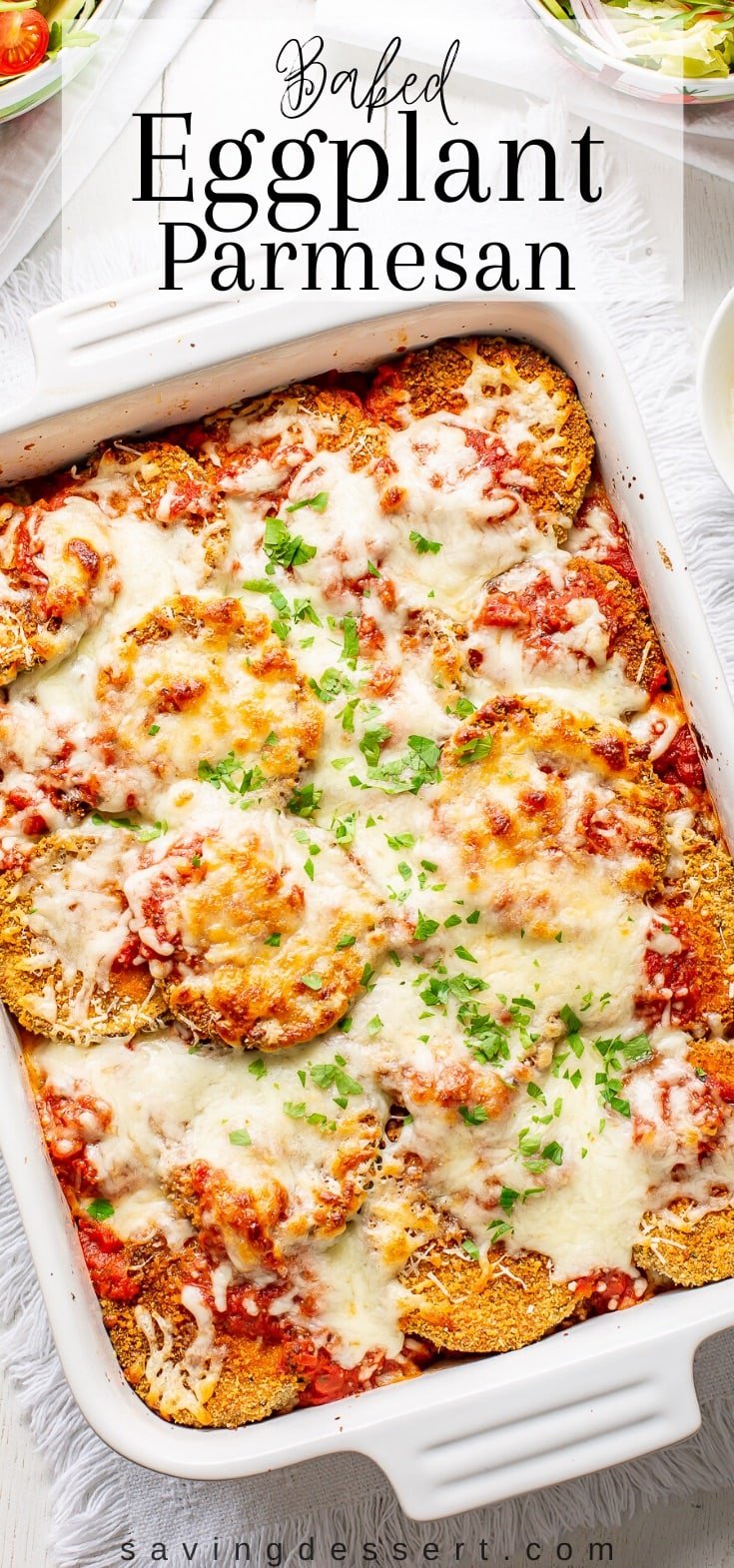 An overhead view of a casserole dish with hot baked eggplant Parmesan.