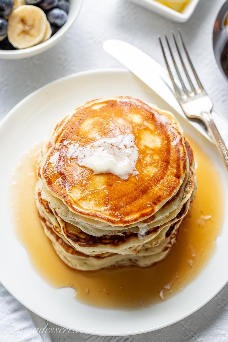 An overhead view of buttermilk pancakes with a pat of butter on top