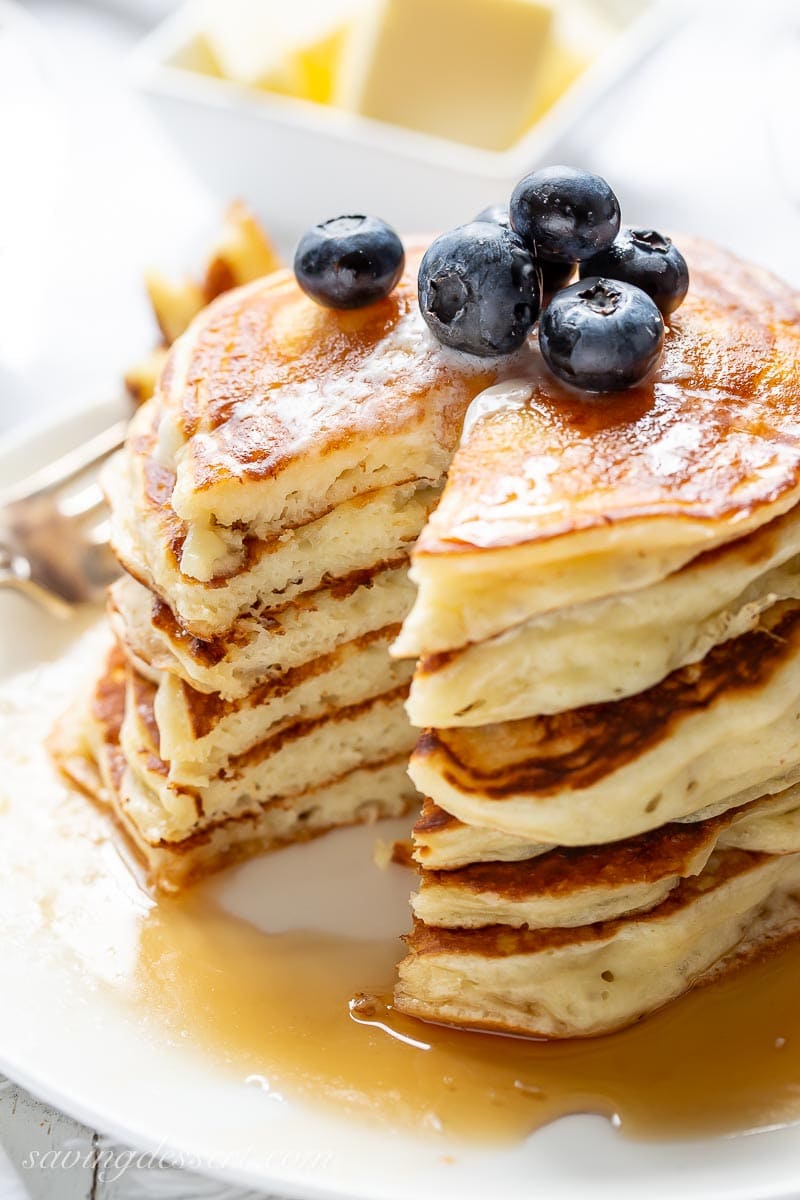 A stack of sliced buttermilk pancakes with blueberries on top