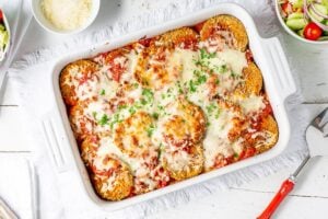 A casserole dish filled with eggplant Parmesan topped with melted mozzarella cheese