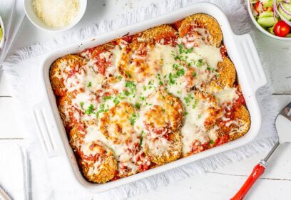 A casserole dish filled with eggplant Parmesan topped with melted mozzarella cheese