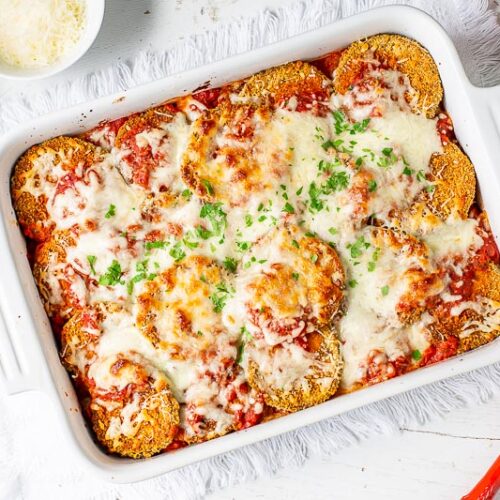 A casserole dish filled with eggplant Parmesan topped with melted mozzarella cheese