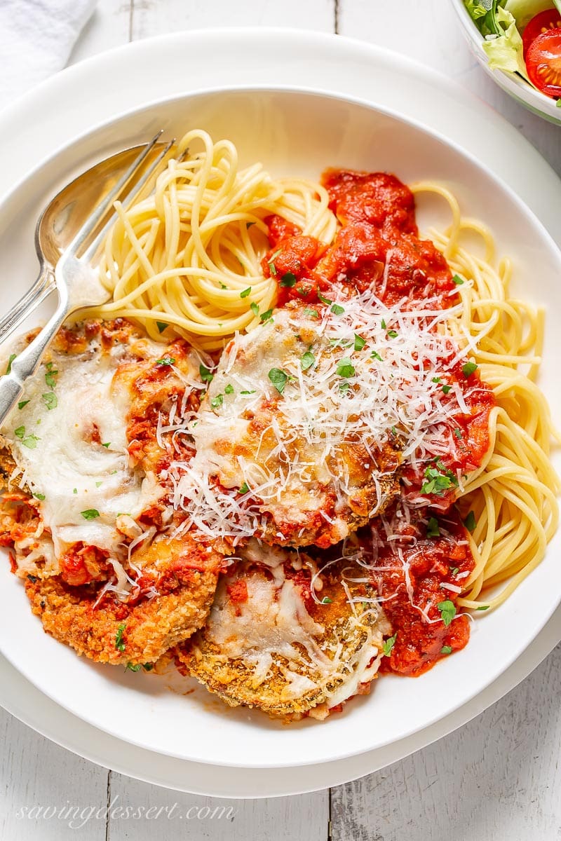 An overhead view of a bowl of spaghetti with marinara sauce and eggplant Parmesan