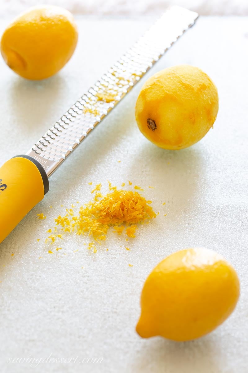 A rasp-style grater, lemon zest and a zested lemon