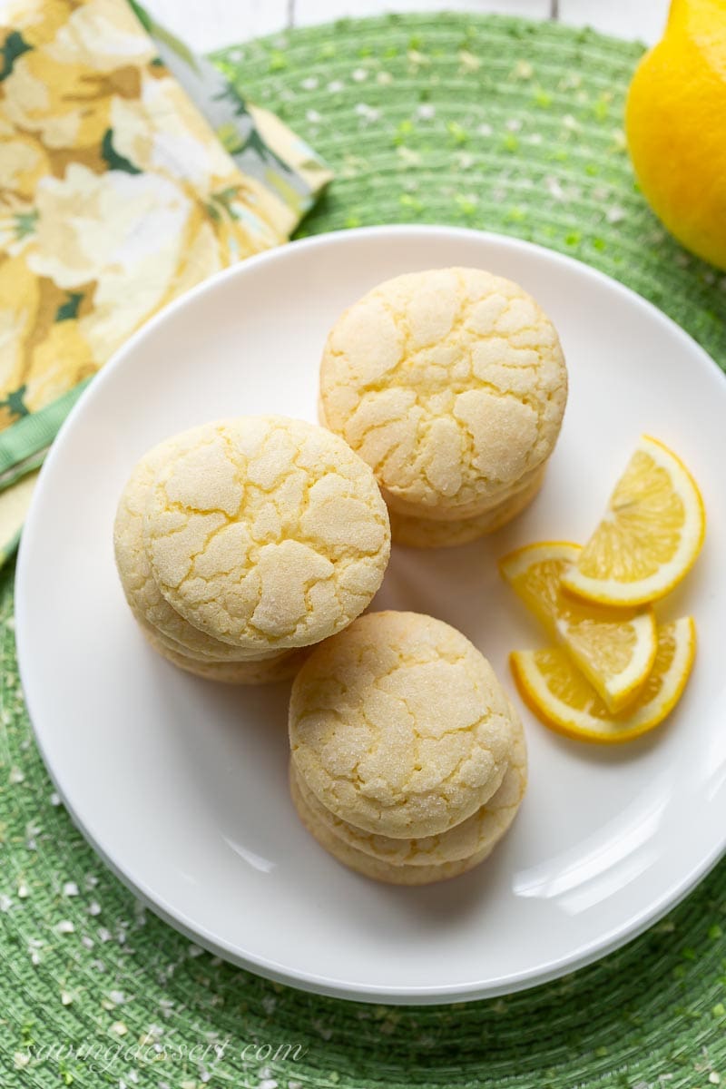 An overhead view of a plate of lemon cookies with lemon wedges