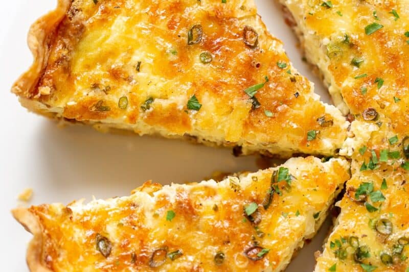 An overhead shot of a sliced quiche lorraine on a platter.