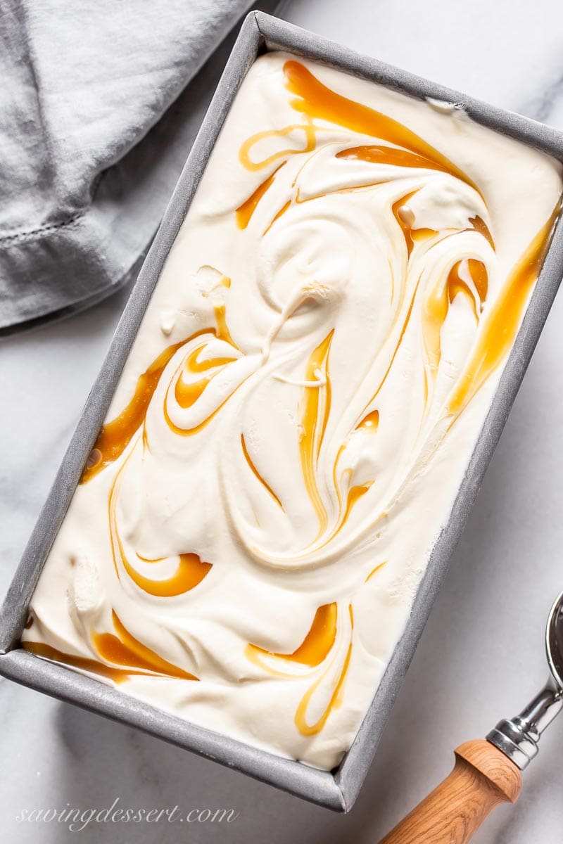 An overhead view of a loaf pan filled with vanilla ice cream with caramel swirls