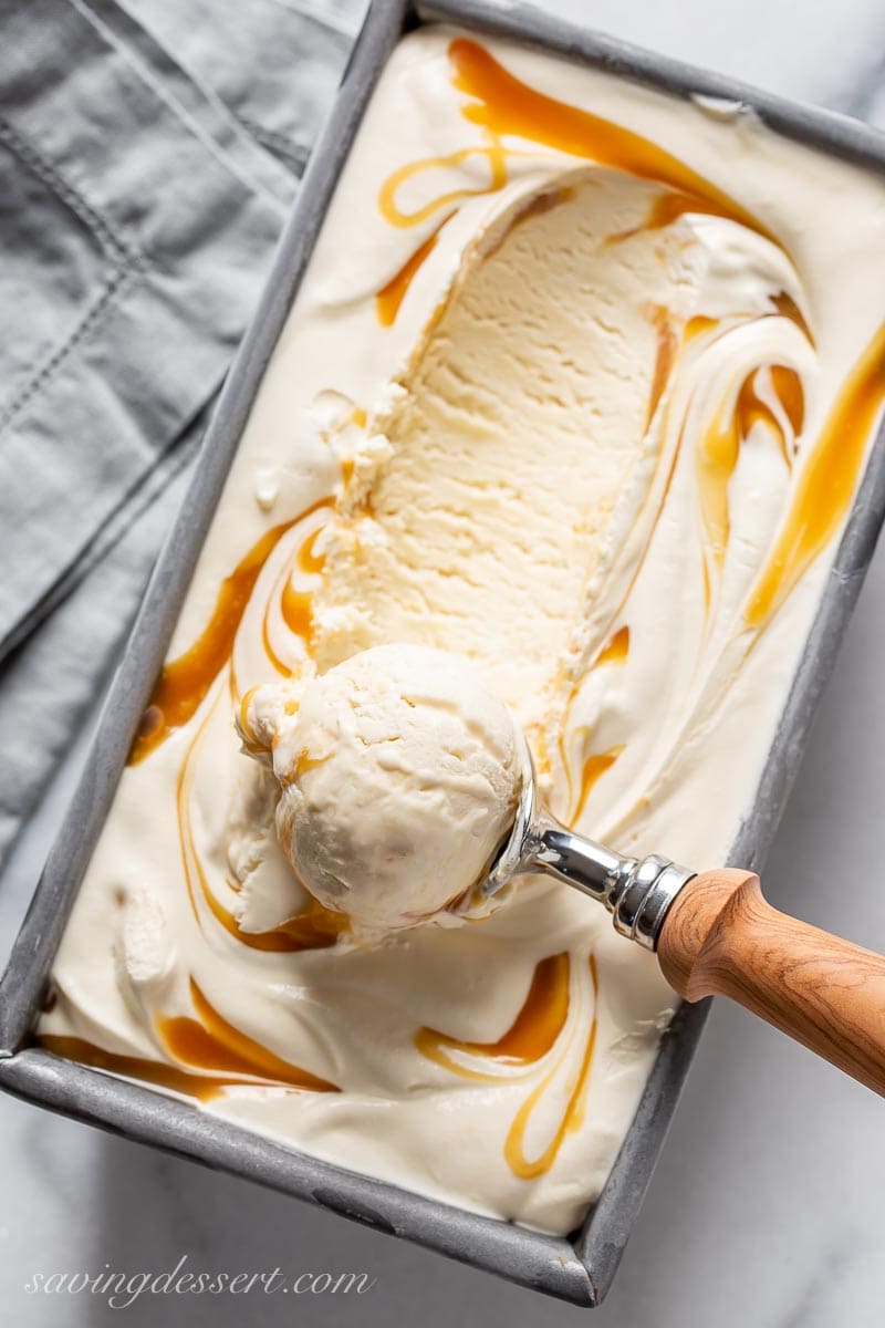 A loaf pan filled with caramel ice cream with a scoop on top