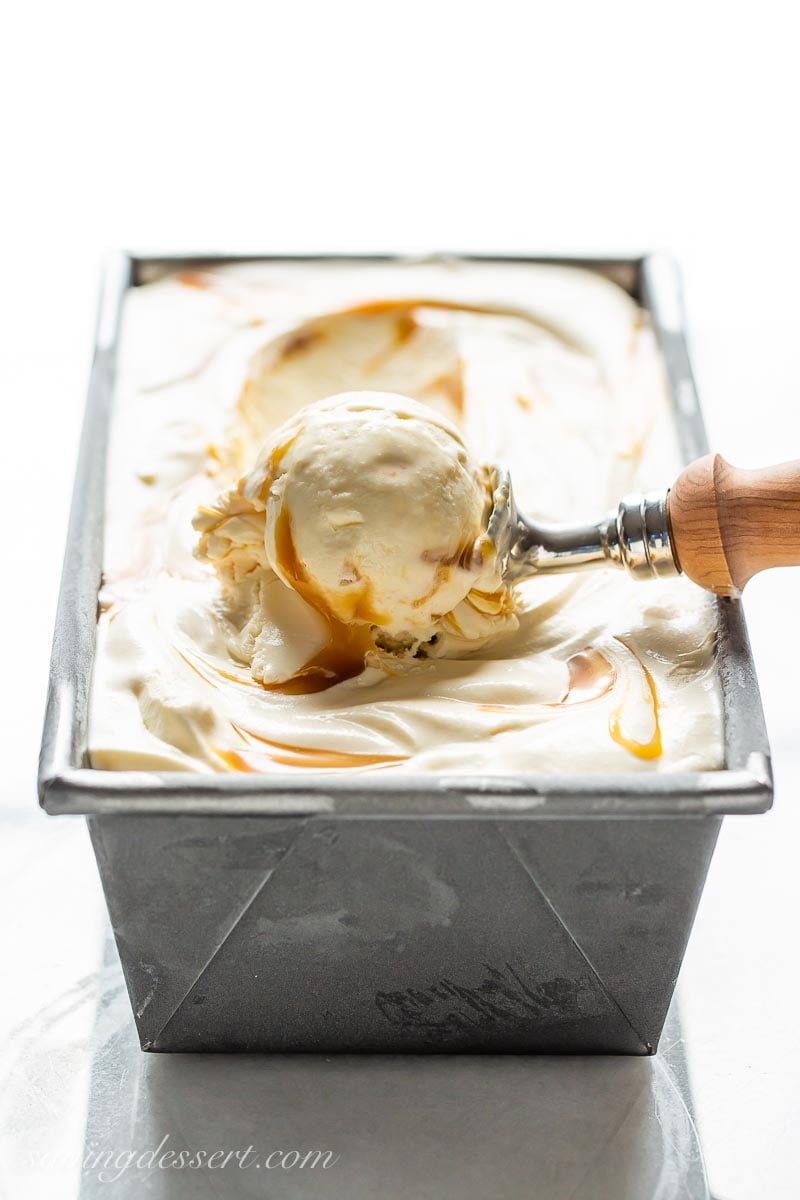 A view of a loaf pan from the side, showing a scoop of frozen vanilla in an ice cream scoop